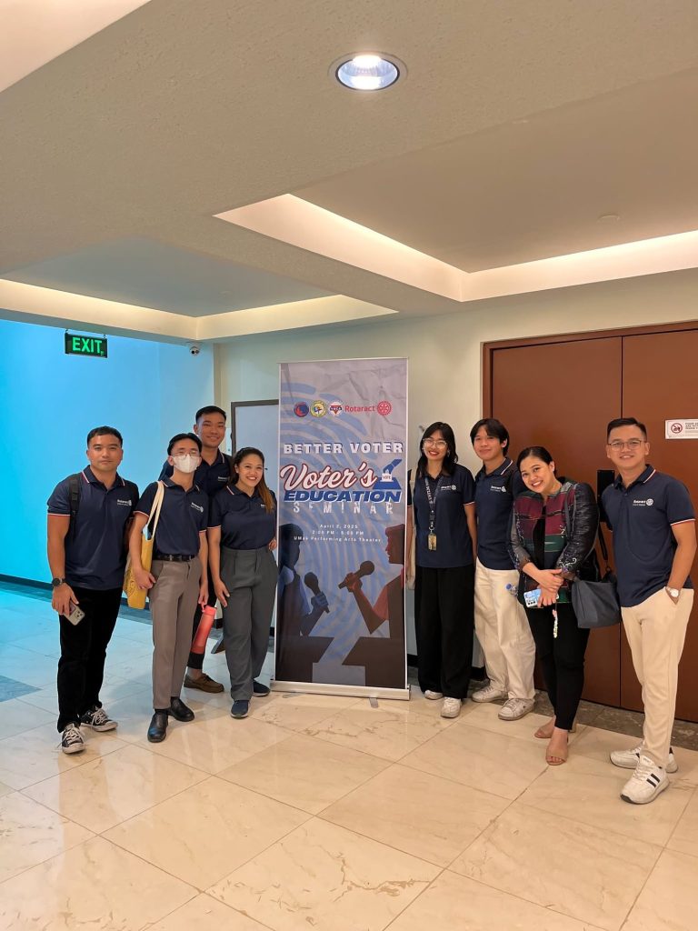 Rotaract Club of Makati members pose beside the “BETTER Voter” seminar banner.