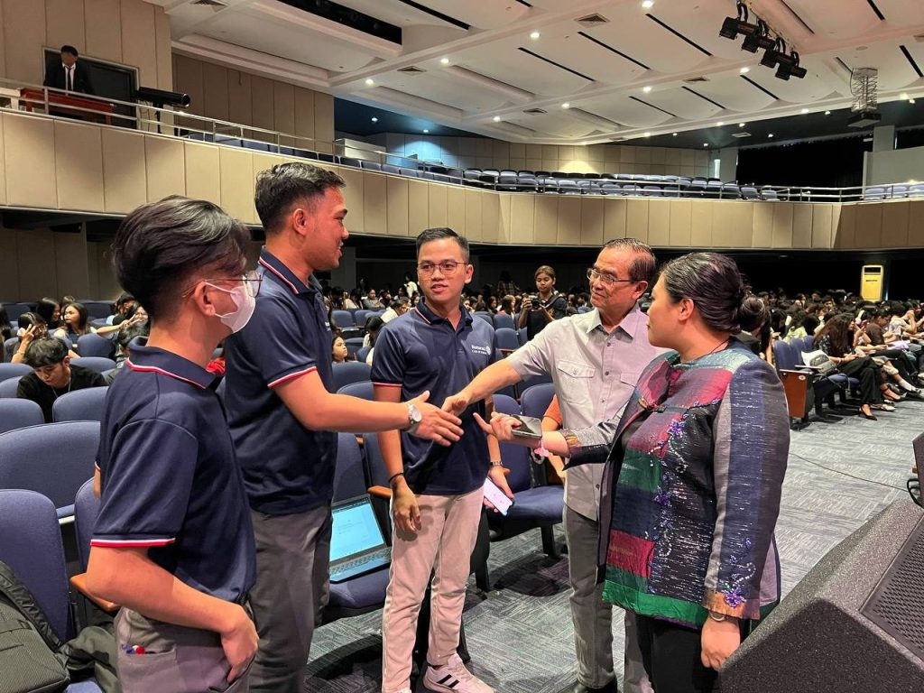 Student volunteers greet a guest in the theater aisle during the seminar.