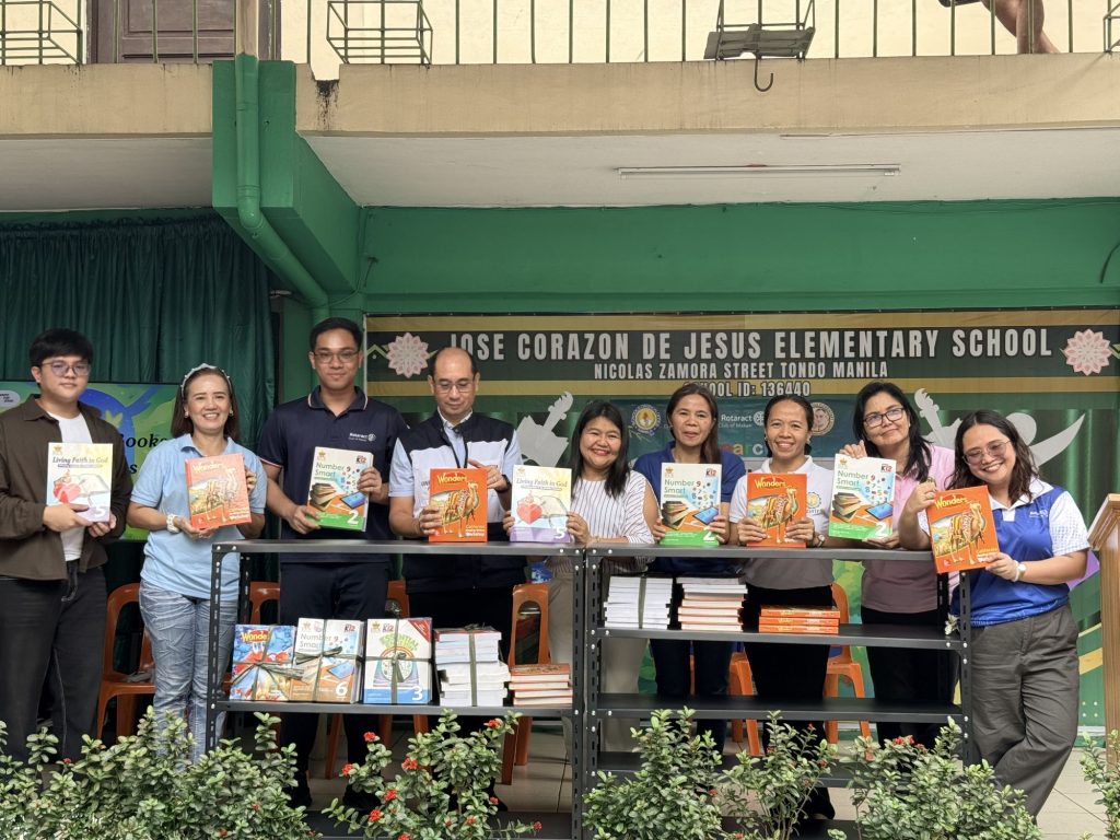 Rotaract Club of Makati members and the school principal hold up the donated books during the EskweLAKBAY culmination.