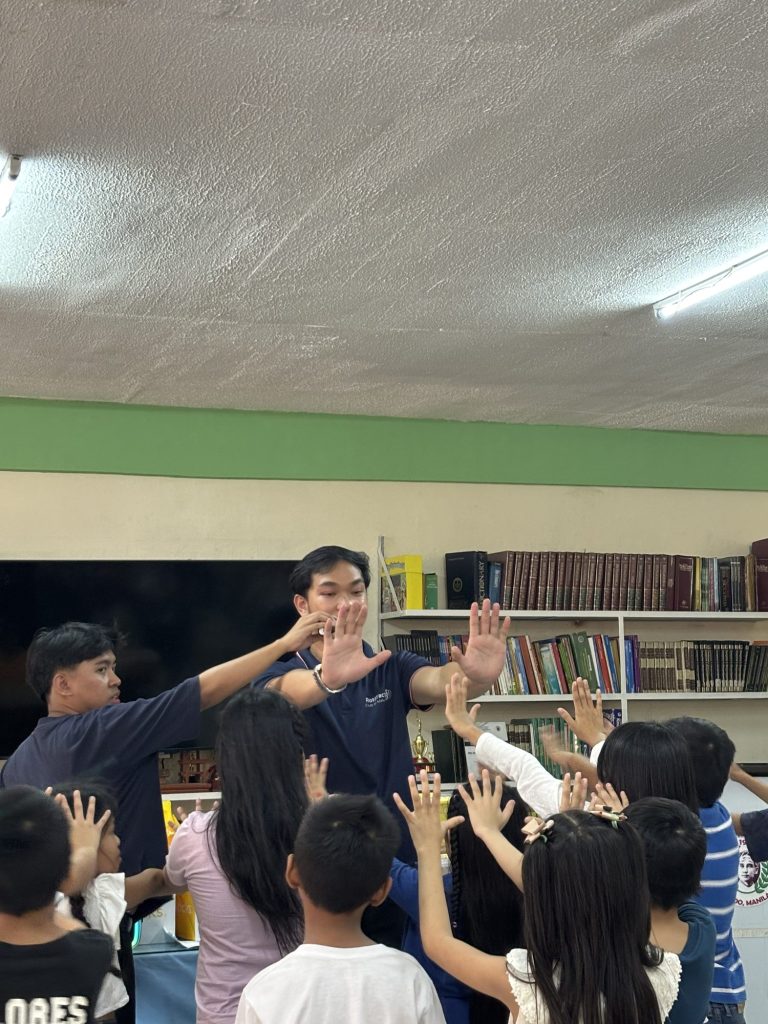 Grade 3 learners raise their hands eagerly during a reading session in the school library.