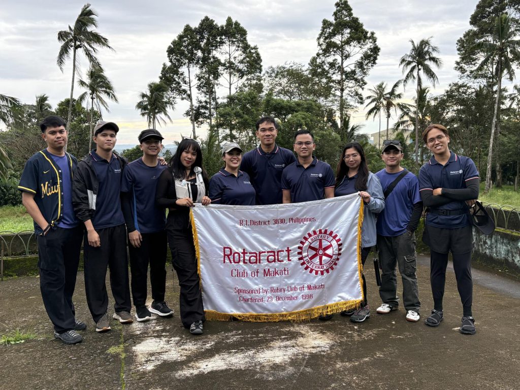 Rotaract Club of Makati members hold the club banner among the palms at Mt. Banahaw de Lucban Botanical Garden.