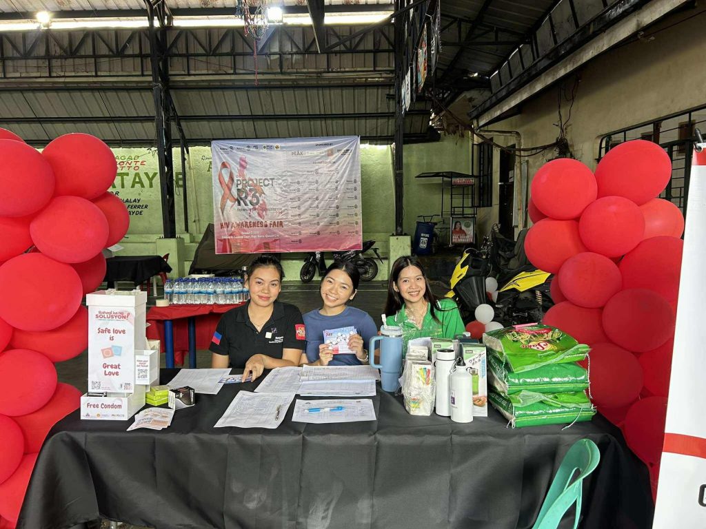 Volunteers staff the information booth, stocked with leaflets and free supplies and framed by red balloons.